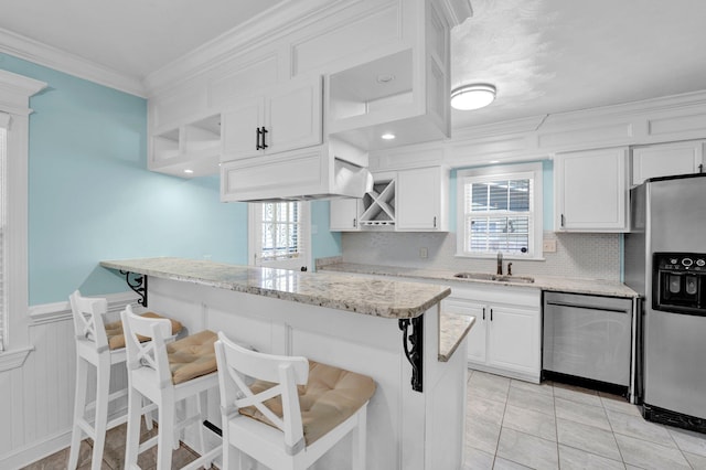 kitchen featuring tasteful backsplash, a kitchen breakfast bar, white cabinets, appliances with stainless steel finishes, and a sink