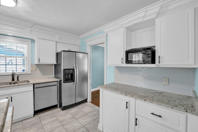 kitchen with backsplash, appliances with stainless steel finishes, a sink, and white cabinetry