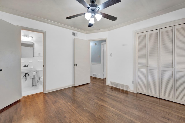 unfurnished bedroom featuring visible vents, a closet, ornamental molding, and wood finished floors