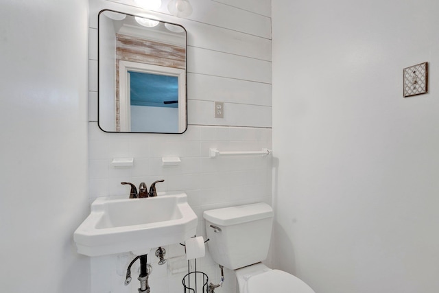 half bathroom featuring tile walls and toilet
