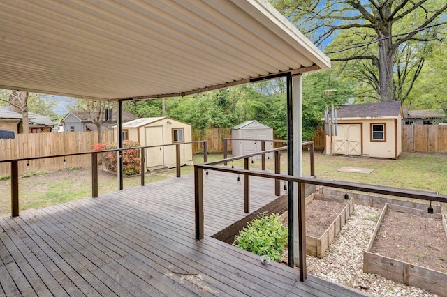 wooden terrace with a shed, a yard, a fenced backyard, an outdoor structure, and a garden
