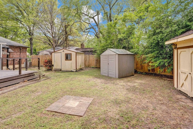 view of yard featuring a storage shed, an outbuilding, a fenced backyard, and a deck