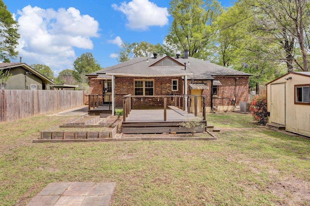 back of house with fence private yard, a garden, brick siding, an outbuilding, and a yard