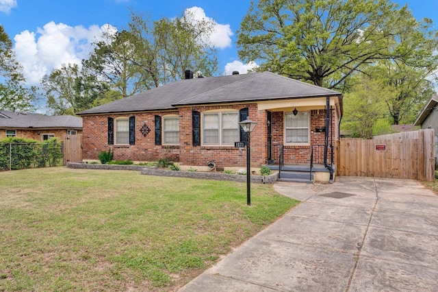 view of front of house featuring driveway, a front lawn, brick siding, fence, and covered porch