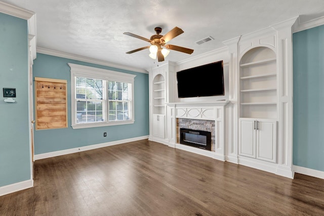 unfurnished living room with baseboards, a stone fireplace, dark wood-style floors, a ceiling fan, and built in shelves