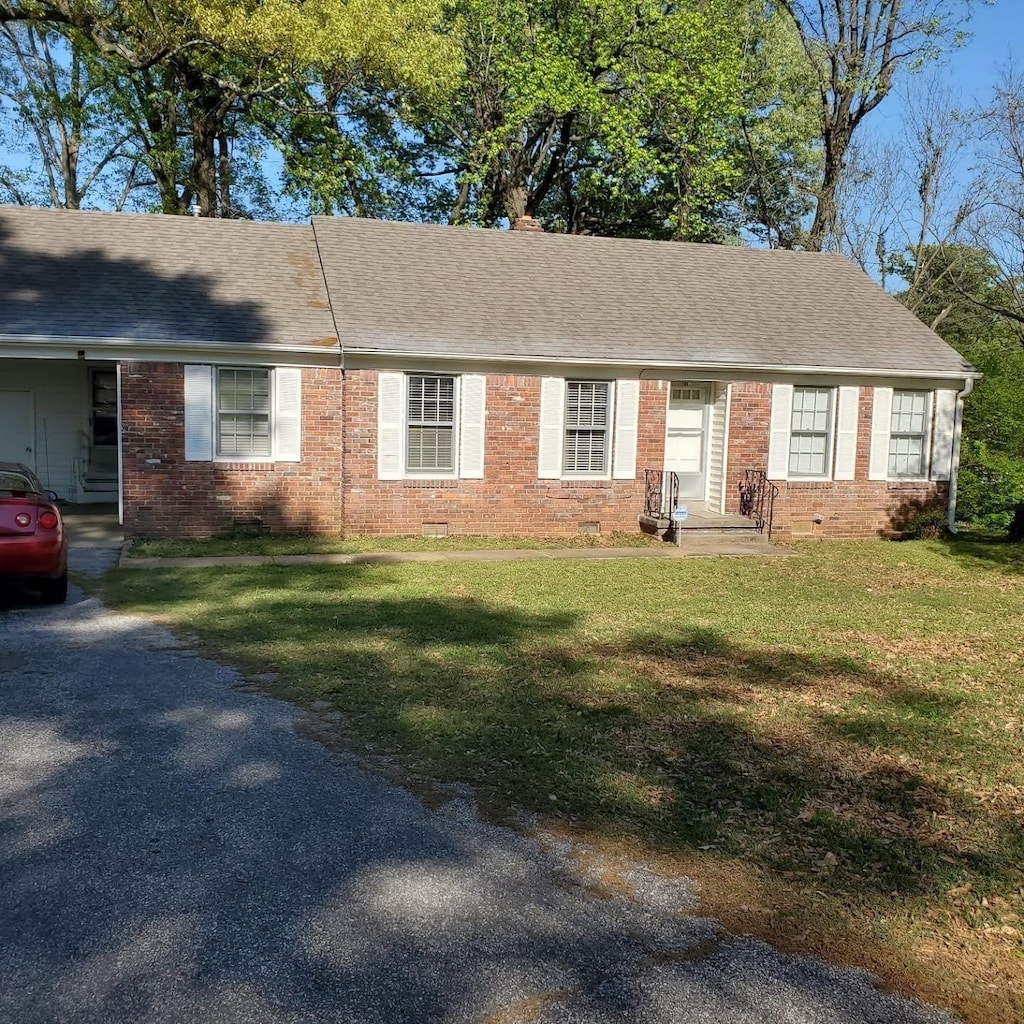 single story home featuring a front yard, entry steps, a shingled roof, and brick siding