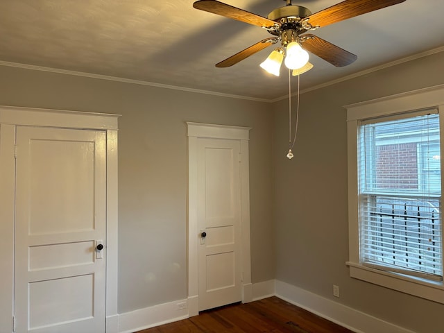 unfurnished bedroom featuring crown molding, baseboards, a ceiling fan, and dark wood finished floors