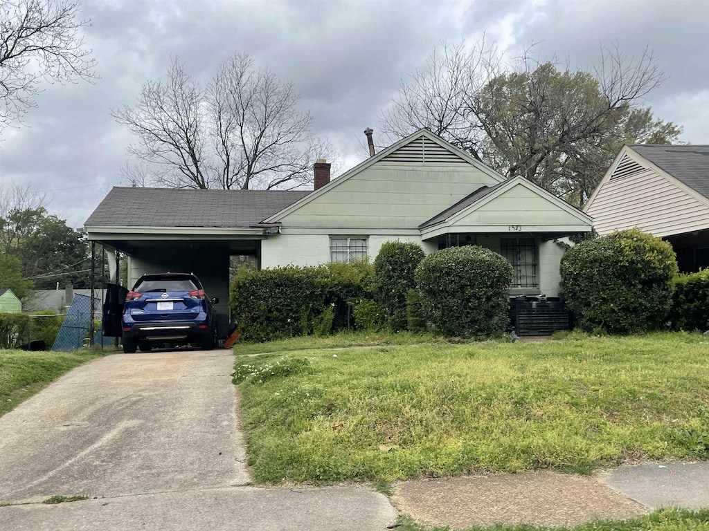 view of front of house with a carport, a chimney, driveway, and a front yard