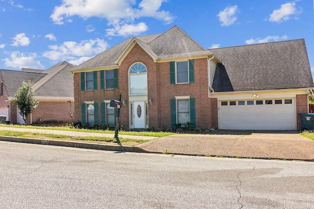 colonial-style house with brick siding, an attached garage, a shingled roof, and concrete driveway