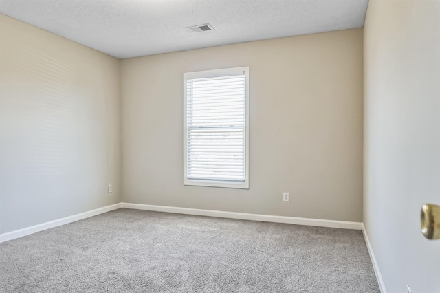 empty room with carpet flooring, visible vents, baseboards, and a textured ceiling