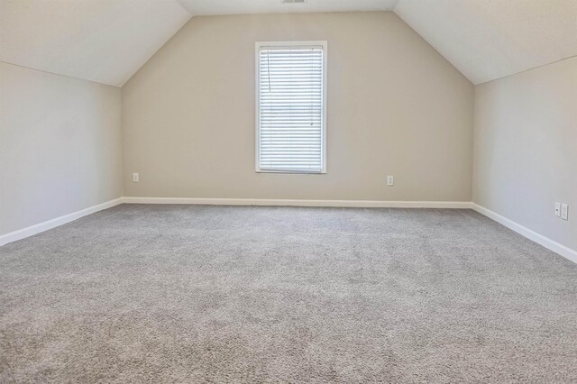 additional living space featuring carpet flooring, baseboards, and vaulted ceiling