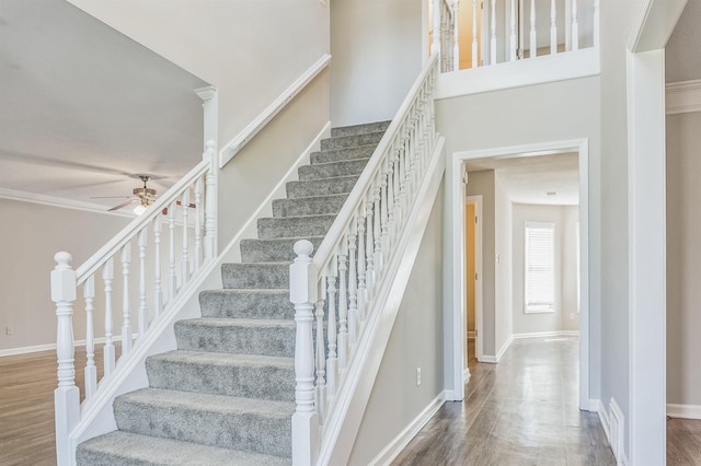 staircase with baseboards, a ceiling fan, and wood finished floors