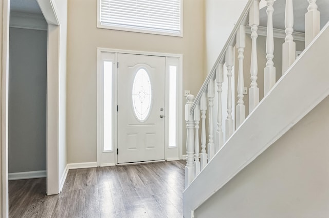 entryway with wood finished floors, a towering ceiling, baseboards, and stairs