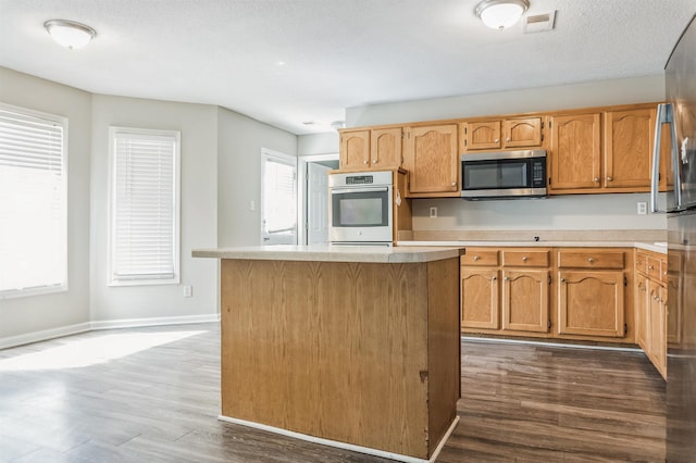 kitchen featuring a center island, light countertops, dark wood finished floors, and stainless steel appliances