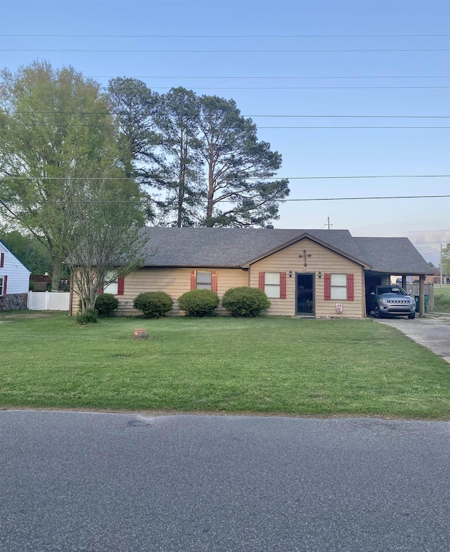 ranch-style home featuring an attached carport, driveway, and a front lawn