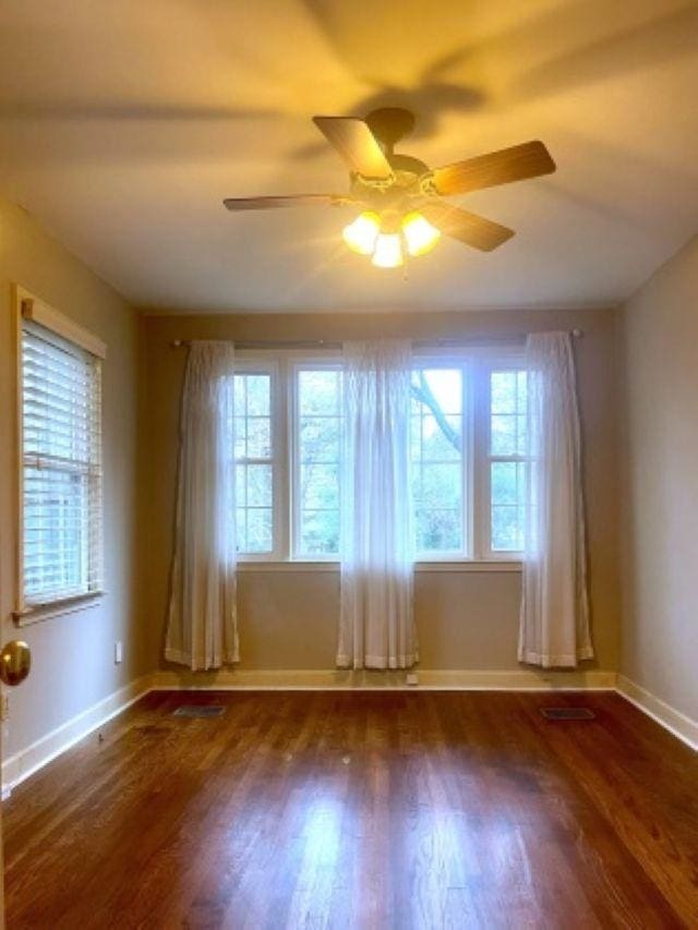 empty room featuring ceiling fan, baseboards, and wood finished floors