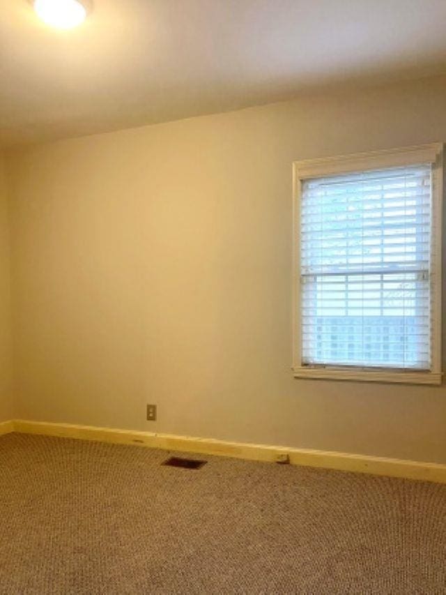carpeted spare room featuring baseboards