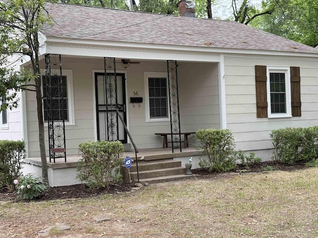 bungalow-style home featuring a porch, roof with shingles, a chimney, and ceiling fan