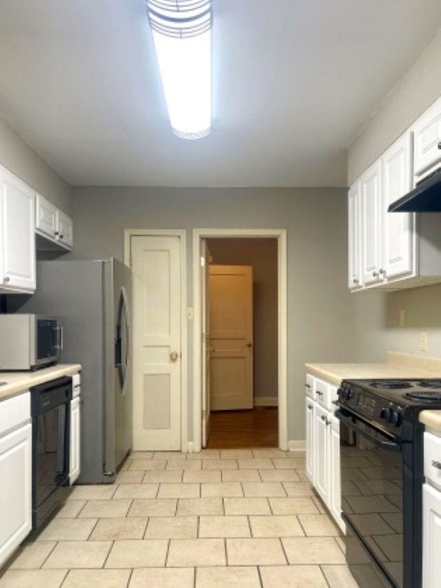 kitchen featuring black appliances, white cabinets, light countertops, wall chimney exhaust hood, and baseboards