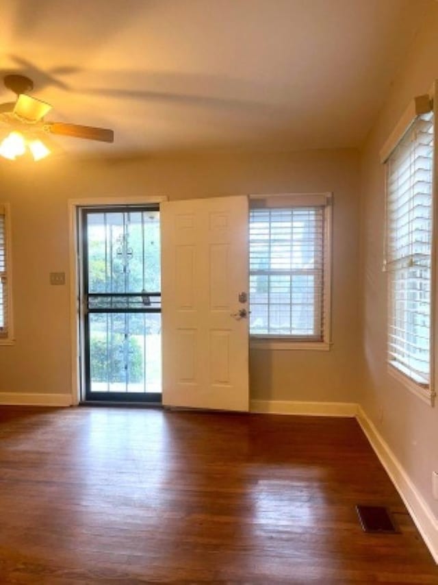entrance foyer with ceiling fan, dark wood-style flooring, healthy amount of natural light, and baseboards