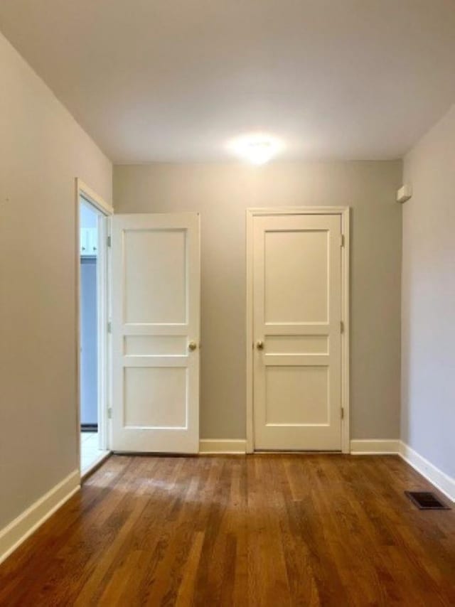 spare room featuring baseboards and wood finished floors