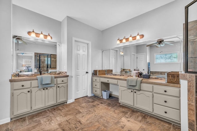 bathroom featuring a tile shower, a ceiling fan, stone finish floor, and vanity