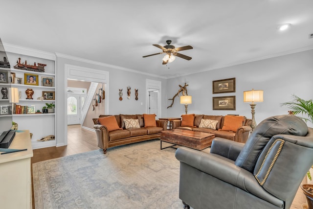 living room with stairway, wood finished floors, a ceiling fan, and ornamental molding