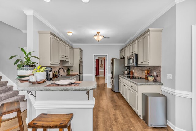 kitchen featuring decorative backsplash, a sink, a breakfast bar, stainless steel appliances, and a peninsula