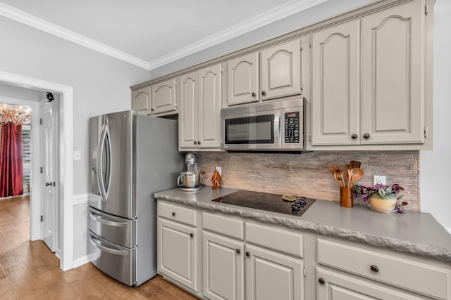 kitchen with light wood-style floors, backsplash, light countertops, ornamental molding, and appliances with stainless steel finishes