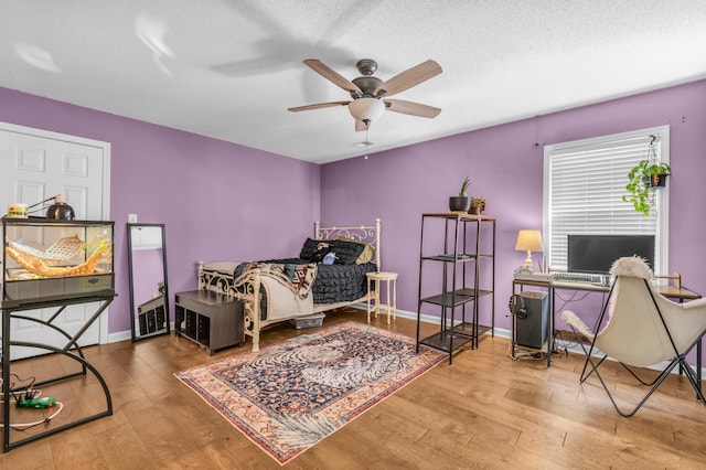 bedroom featuring a textured ceiling, ceiling fan, hardwood / wood-style flooring, and baseboards