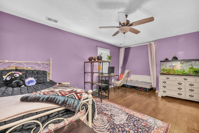 bedroom with visible vents, wood finished floors, a ceiling fan, and a textured ceiling