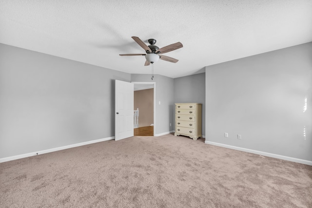 unfurnished bedroom featuring a ceiling fan, a textured ceiling, carpet, and baseboards