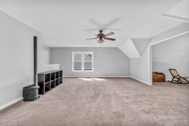 additional living space featuring a textured ceiling, carpet flooring, ceiling fan, and baseboards