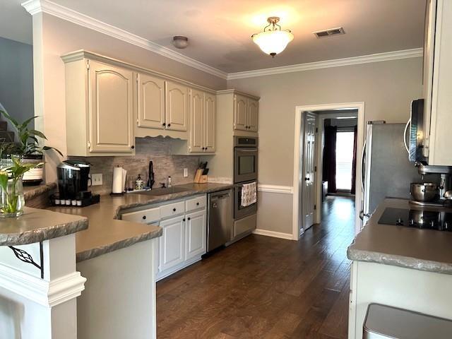 kitchen featuring a sink, black appliances, a peninsula, dark wood-type flooring, and visible vents