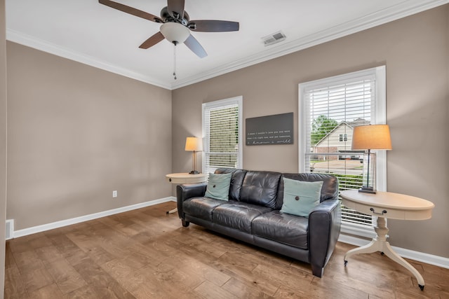 sitting room featuring baseboards, visible vents, wood finished floors, and crown molding