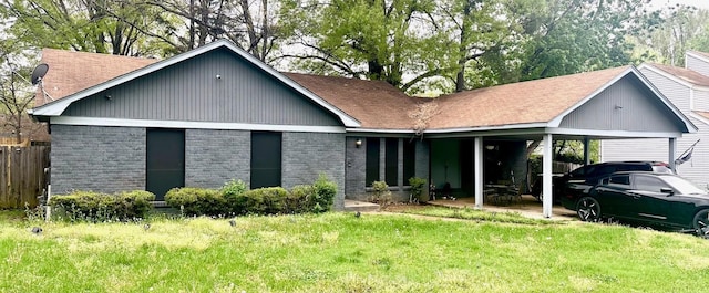 view of front of property with an attached carport, a front yard, brick siding, and fence
