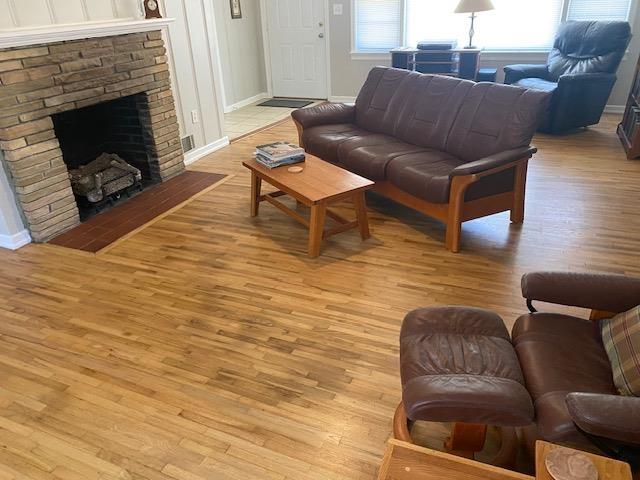 living room featuring visible vents, light wood-style flooring, baseboards, and a fireplace