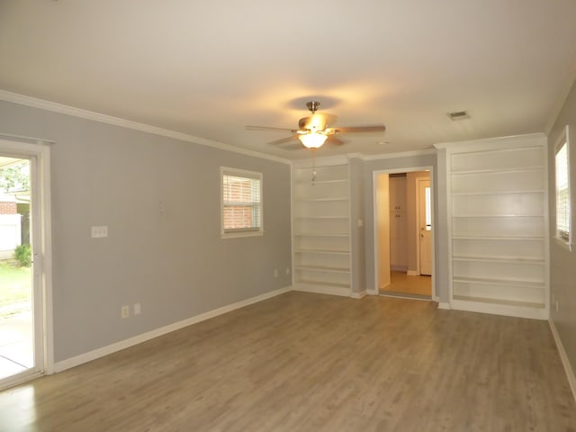 empty room featuring crown molding, baseboards, and wood finished floors