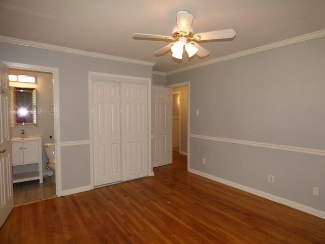 unfurnished bedroom with a closet, baseboards, ornamental molding, connected bathroom, and wood finished floors