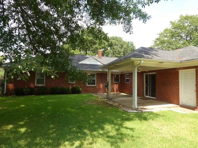 rear view of house featuring a chimney, a yard, a patio area, and brick siding