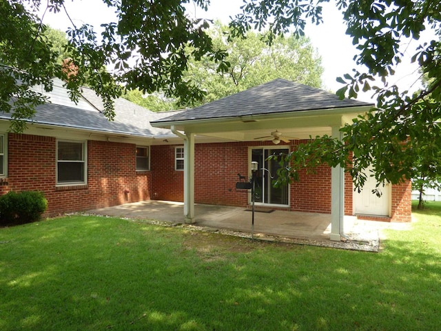 rear view of property featuring a patio area, ceiling fan, brick siding, and a yard