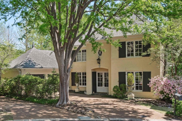 exterior space featuring french doors, a shingled roof, and brick siding