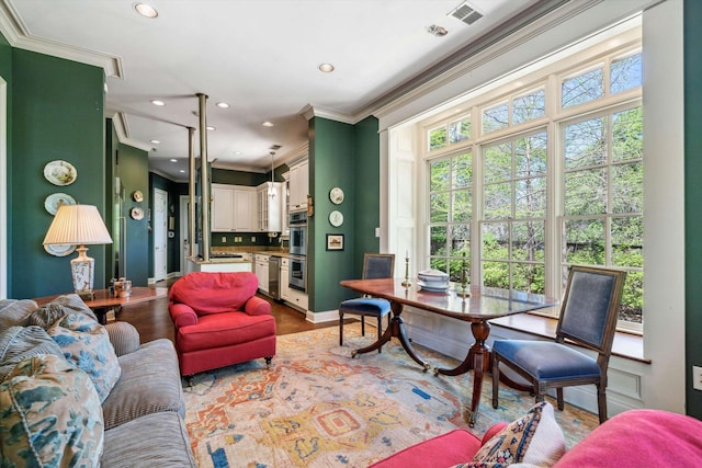 living room featuring baseboards, ornamental molding, recessed lighting, visible vents, and wood finished floors