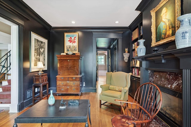 sitting room with crown molding, wood finished floors, baseboards, and stairs
