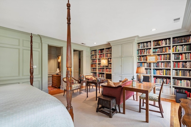 bedroom with crown molding, visible vents, recessed lighting, and a decorative wall