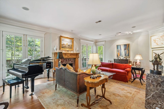 living area with plenty of natural light, visible vents, ornamental molding, and wood finished floors