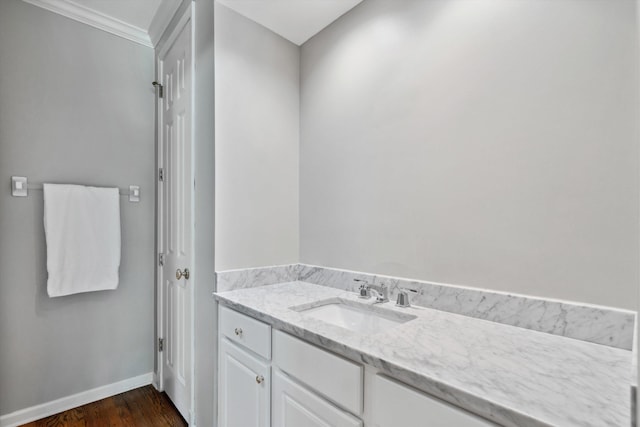bathroom featuring crown molding, baseboards, vanity, and wood finished floors