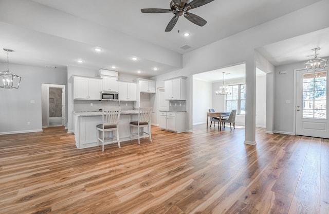 175 Valleyview Ln, Oakland, TN 38060 - kitchen featuring a kitchen island with sink, a kitchen bar, stainless steel microwave, white cabinetry, and light wood-style flooring
