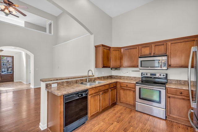 kitchen featuring a sink, brown cabinets, a high ceiling, and stainless steel appliances
