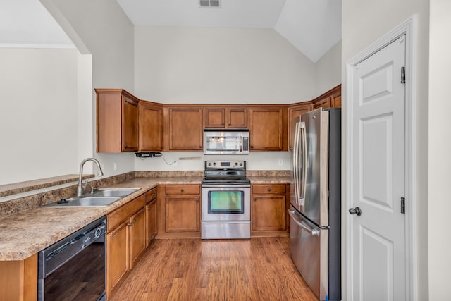 kitchen with stainless steel appliances, a sink, visible vents, brown cabinets, and high vaulted ceiling